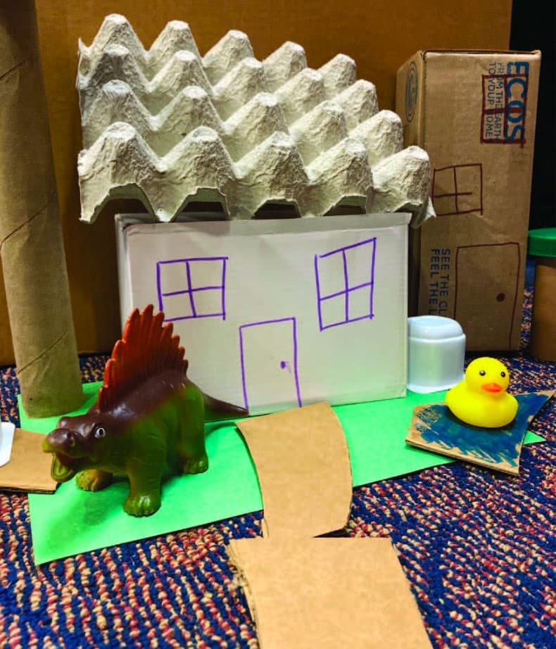 Cardboard house with dinosaur toys
