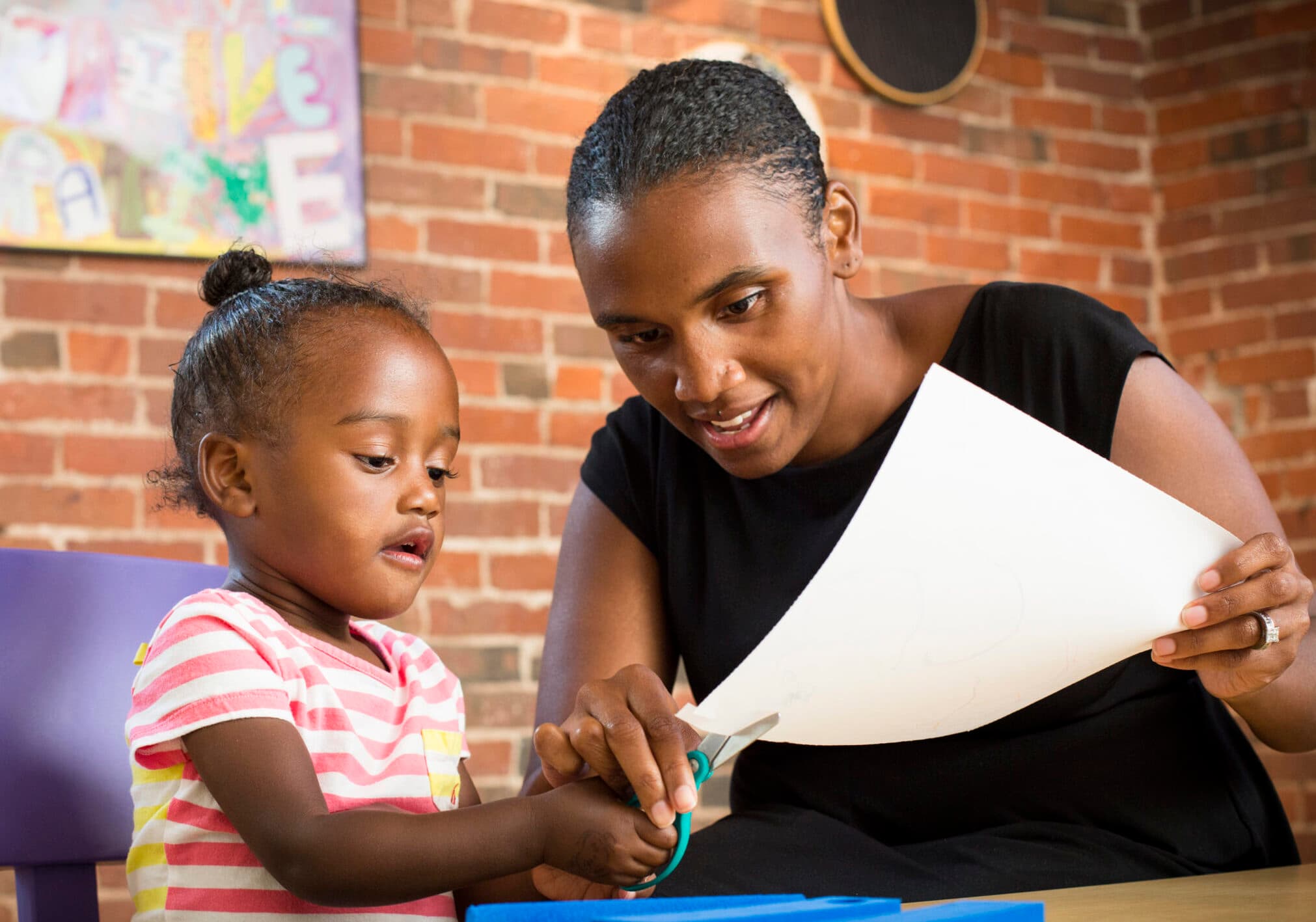 adult helping child to use scissors